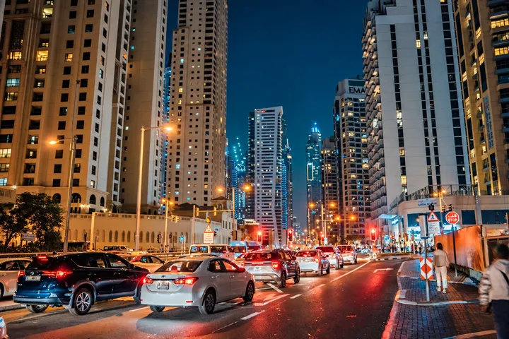 Night traffic beneath illuminated Dubai towers; edited context photograph by Raimond Klavins, not the reported shoot.
