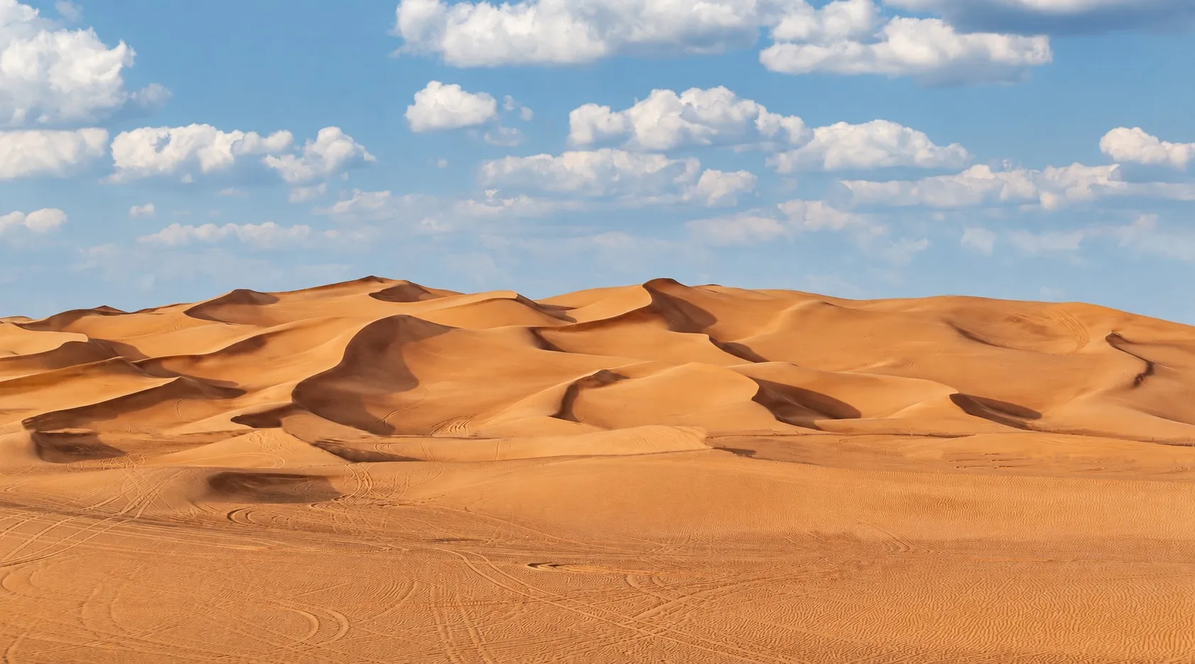 Wind-shaped sand dunes and vehicle tracks at Lahbab, Dubai.