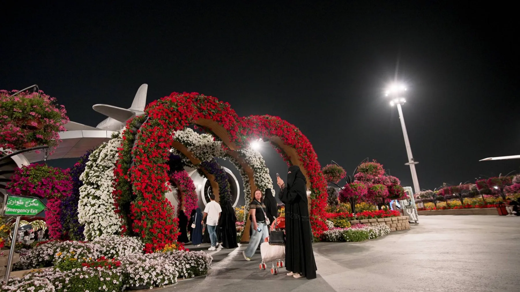 Visitors walk beneath red, white and purple flower arches at Boulevard Flowers in Riyadh