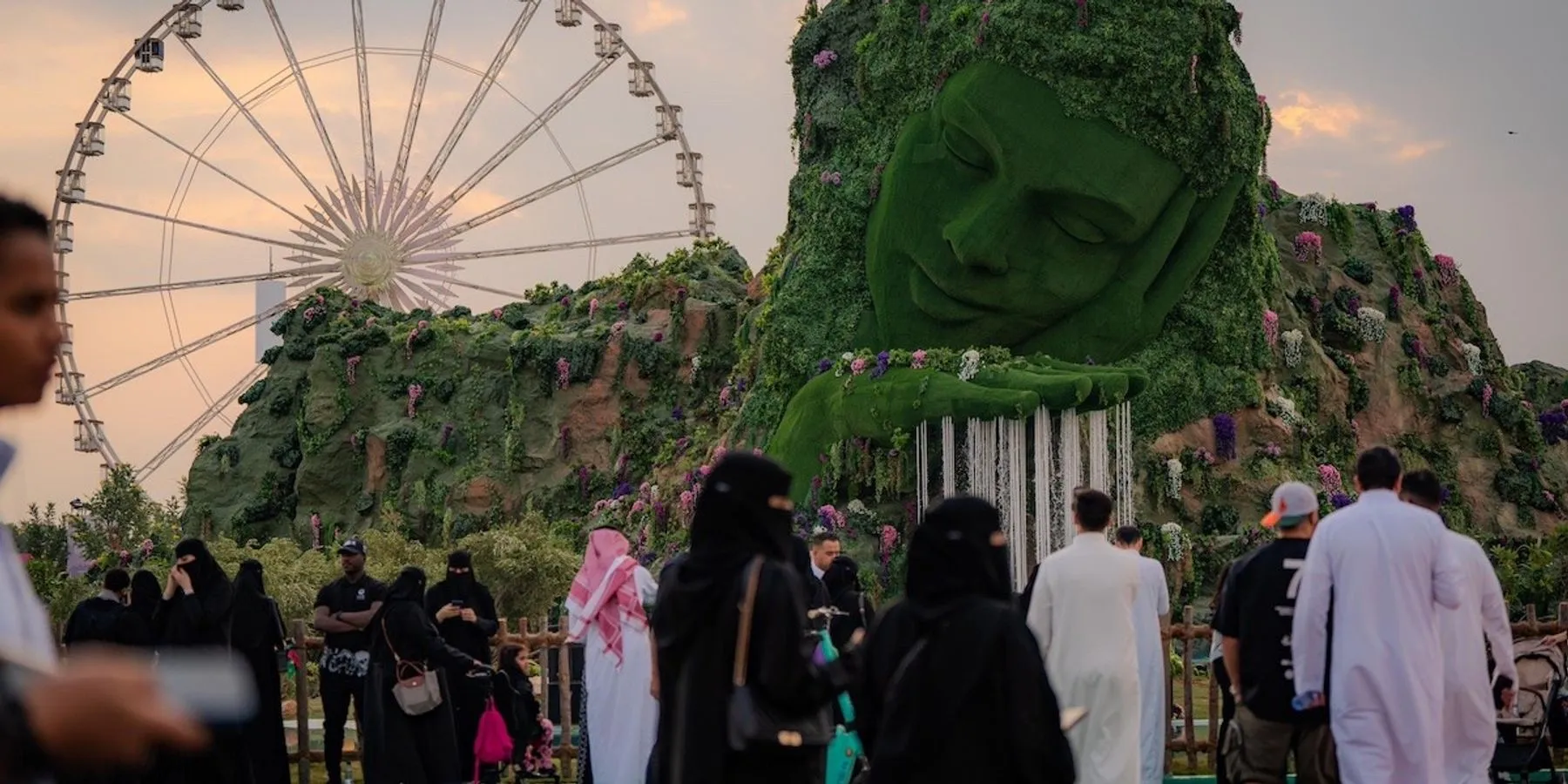 Families explore Wonder Garden in Riyadh beside its giant planted face sculpture and Ferris wheel