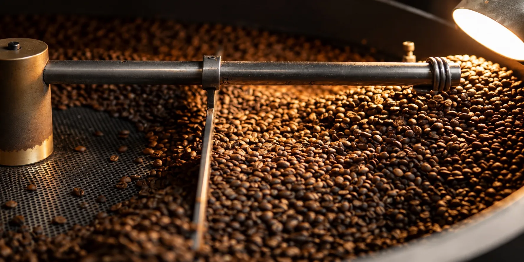 Coffee beans turning in a roaster under warm light