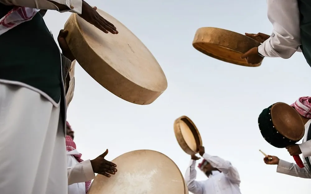 Performers beat frame drums at a folk festival in Al Birk, Asir
