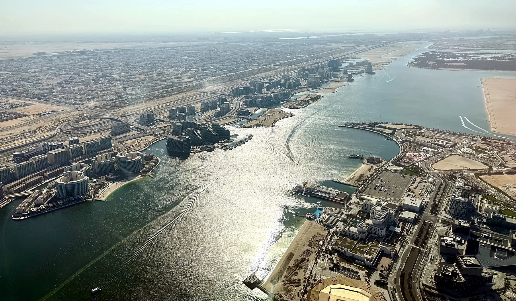 Aerial view across Yas Bay with Etihad Arena in the foreground and waterfront buildings along the channel